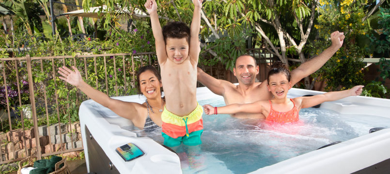 happily family in hot tub with hands in the air for springtime