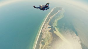 one man skydiving over ocean